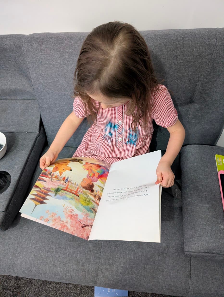 Young girl smiling while reading her personalized LunaListen storybook - a custom printed children's book featuring her as the main character